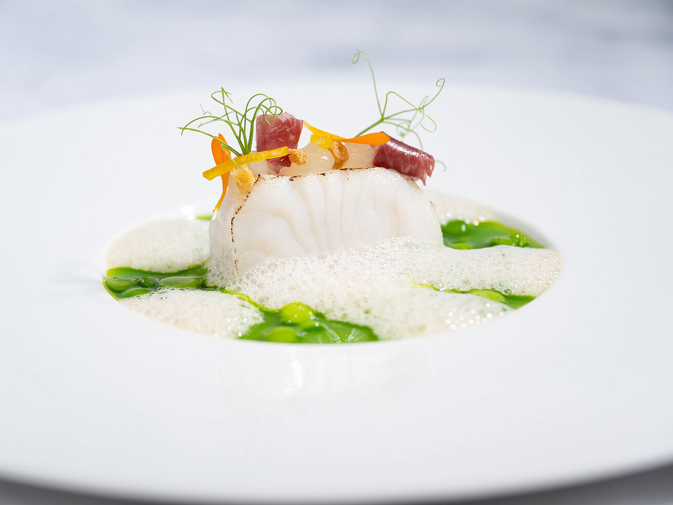 Kabeljau kunstvoll angerichtet mit feinen Kräutern, Beilagen und Sauce im Sternerestaurant Orangerie.