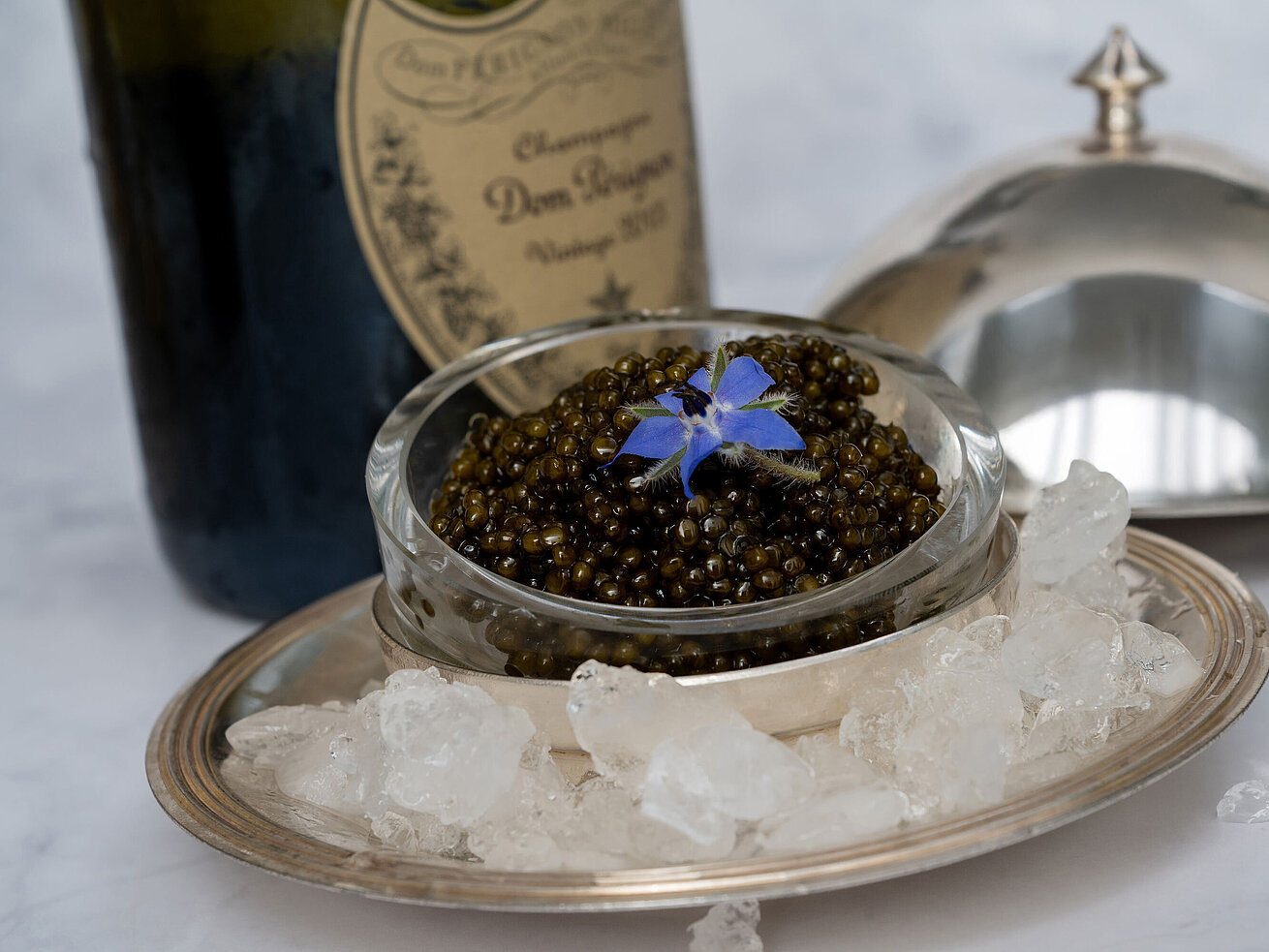 Feiner Kaviar stilvoll serviert auf Eis mit Silberhaube im Sternerestaurant Orangerie.